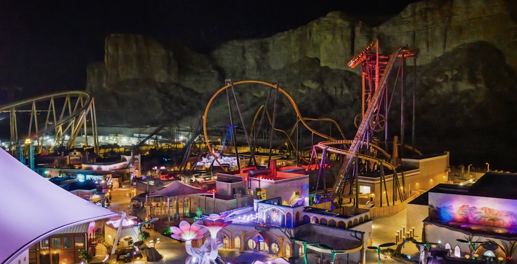 Roller coasters and attractions illuminated at night in Six Flags Qiddiya City, Saudi Arabia.