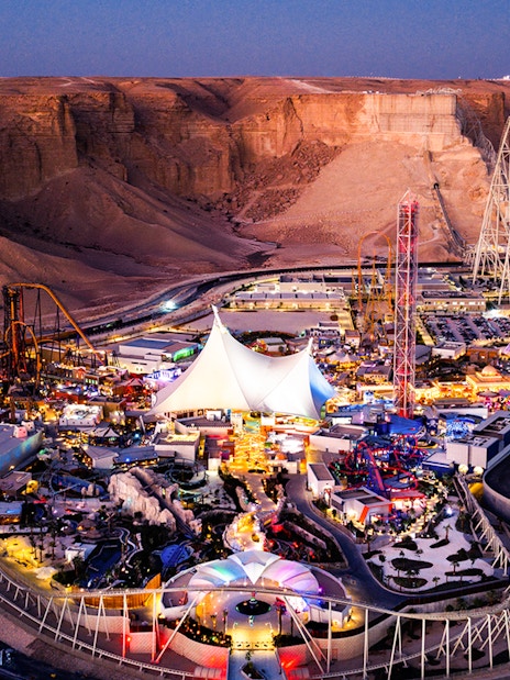 Aerial view of Six Flags Qiddiya City amusement park with roller coasters and attractions.