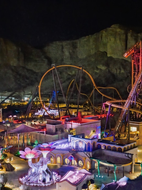 Roller coasters and attractions illuminated at night in Six Flags Qiddiya City, Saudi Arabia.